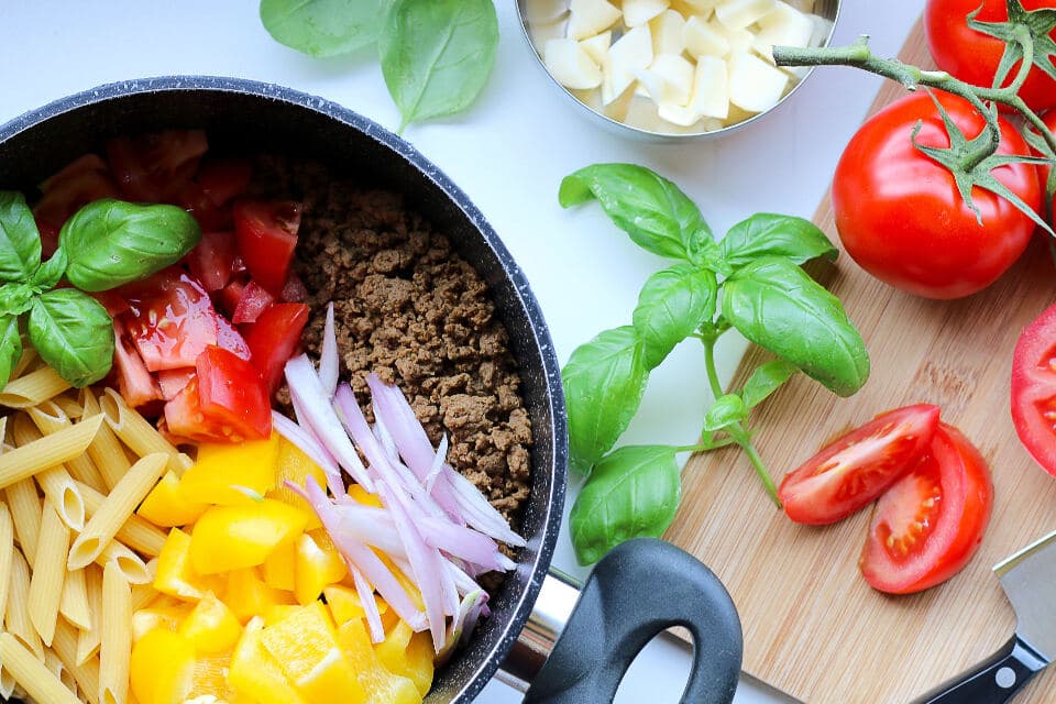 Sartén con pasta, verduras frescas y albahaca
